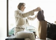 Senior woman admiring purchase in shop window seat — Stock Photo