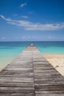 Woman on wooden pier on tropical beach — Stock Photo