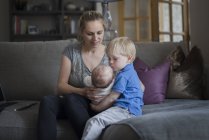 Mother helping son to hold baby brother — Stock Photo