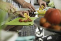 Обрезанный образ пары резки овощей на кухне — стоковое фото