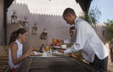 Kellner serviert jungen Paaren Frühstück, Marrakesch, Marokko — Stockfoto