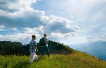 Father and son hiking on grassy hilltop — Stock Photo