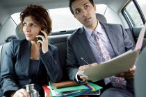Бизнесмены на заднем сиденье машины, женщина на телефоне — стоковое фото