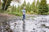 Ragazzo che indossa stivali di gomma nel fiume poco profondo — Foto stock