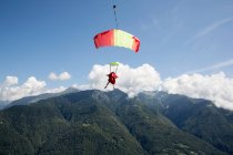Fallschirmspringerin unter ihrem Fallschirm im freien Flug in den blauen Himmel, Locarno, Tessin, Schweiz — Stockfoto