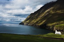Flanc de montagne herbeux sur le littoral avec ciel nuageux — Photo de stock