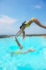Four people jumping into swimming pool — Stock Photo