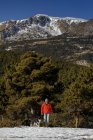 Человек выгуливает собаку в заснеженном горном пейзаже — стоковое фото