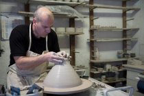 Ceramista maschio che modella la pentola di argilla sulla ruota della ceramica in officina — Foto stock
