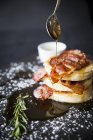 Breakfast bacon crumpet with maple syrup pouring from spoon onto slate — Stock Photo