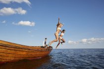 Women jumping from boat in blue ocean — Stock Photo