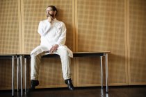 Dottore in camice bianco seduto sul tavolo — Foto stock