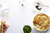 Draufsicht auf den Esstisch mit Huhn-Lauch-Torte, grünen Bohnen und Schokoladenpudding-Dessert — Stockfoto