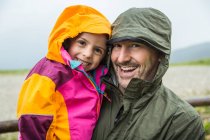 Padre e hija en chaquetas impermeables - foto de stock