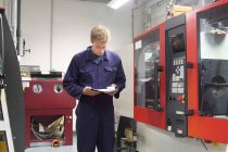 Engenheiro masculino verificando papelada de máquinas na fábrica — Fotografia de Stock