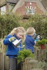 Schuljunge und Mädchen gießen Pflanzen im Garten — Stockfoto