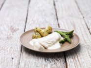 Haddock fillet with mornay sauce, served with asparagus and new potatoes — Stock Photo