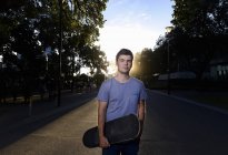 Portrait de jeune homme tenant skateboard — Photo de stock
