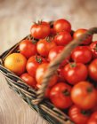 Food, fruit and vegetables, fresh vine tomatoes and orange in a wicker basket — Stock Photo