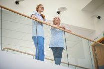 Дві жінки медсестри чекають на лікарняний атріумний балкон — стокове фото