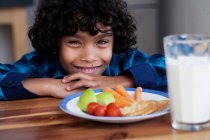 Хлопчик посміхається з закусками і склянкою молока — стокове фото