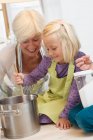 Chica con la abuela cocinar mermelada - foto de stock