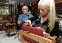 Senior beobachtet Auszubildende beim Auftragen von Blattgold auf Buchrücken in traditioneller Buchbinderei — Stockfoto