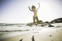 Frau springt am Strand — Stockfoto