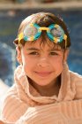 Portrait of young girl with swimming goggles, wrapped in a towel — Stock Photo