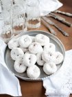 Tray of sugar powdered donuts with glasses of water — Stock Photo