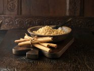 Bastoncini di cannella legati con spago e zucchero di canna in ciotola di legno — Foto stock