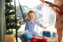 Boy and sister playing toy drum kit and guitar on christmas day — Stock Photo