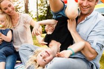Отец переворачивает дочь с ног на голову на семейном пикнике в парке — стоковое фото