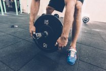 Cropped shot of man preparing barbell in cross training gym — Stock Photo