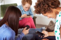 Три друзі-жінки використовують смартфони — стокове фото
