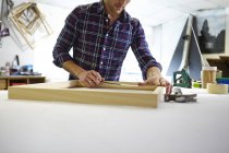 Mid adult man measuring frame on workbench in picture framers workshop — Stock Photo