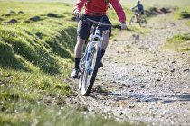 Cropped image of Cyclists cycling down dirt track — Stock Photo
