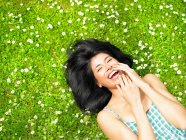 Woman smiling, surrounded by daisies — Stock Photo