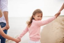 Family holding hands walking on beach — Stock Photo