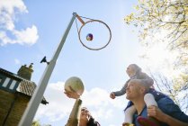 Familie wirft Basketball durch Basketballkorb — Stockfoto