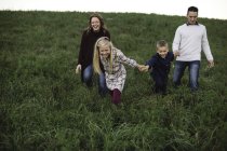 Família de mãos dadas caminhando no campo — Fotografia de Stock