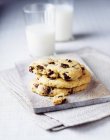 Three chocolate chip cookies with glass of milk — Stock Photo