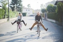 Jovem casal de bicicleta com as pernas para fora — Fotografia de Stock