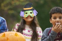Mädchen trägt Maske mit Geschwistern im Freien — Stockfoto