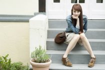 Portrait de jeune femme assise sur les marches de la maison — Photo de stock