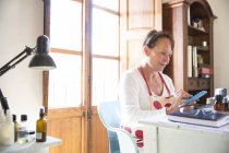 Reife Frau textet auf Büro-Smartphone in handgemachter Seifenmanufaktur — Stockfoto