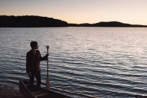 Mitte erwachsene Frau steht am Ufer und blickt über den See — Stockfoto