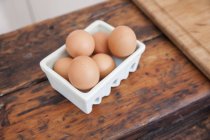 Scatola di uova sul bancone della cucina in legno — Foto stock