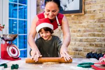 Madre e hijo haciendo galletas de Navidad en casa - foto de stock