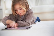 Mädchen auf dem Boden liegend und mit digitalem Tablet — Stockfoto
